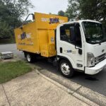 Yellow Out Junk Out removal truck parked beside a residential driveway