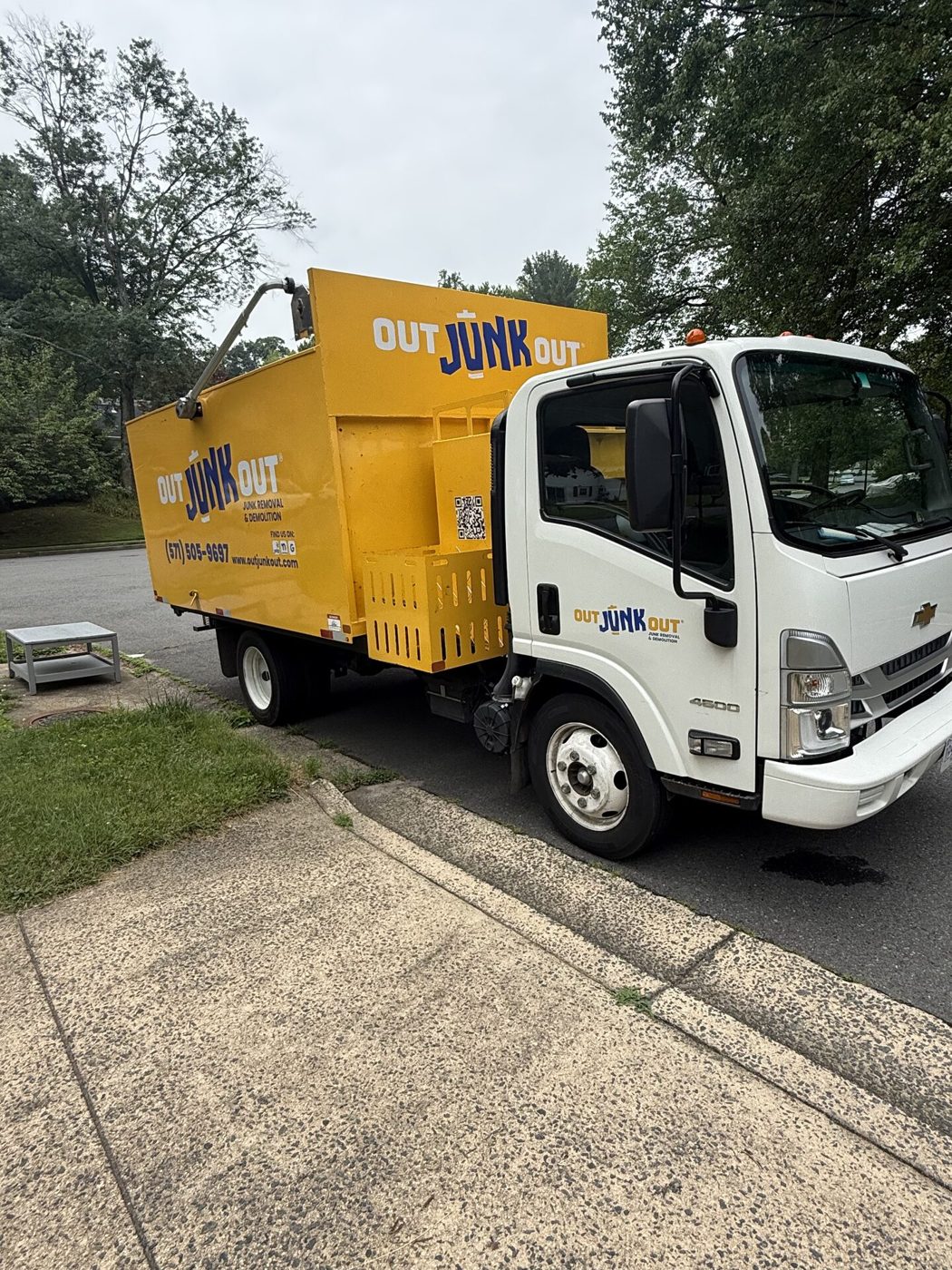 Yellow Out Junk Out removal truck parked beside a residential driveway
