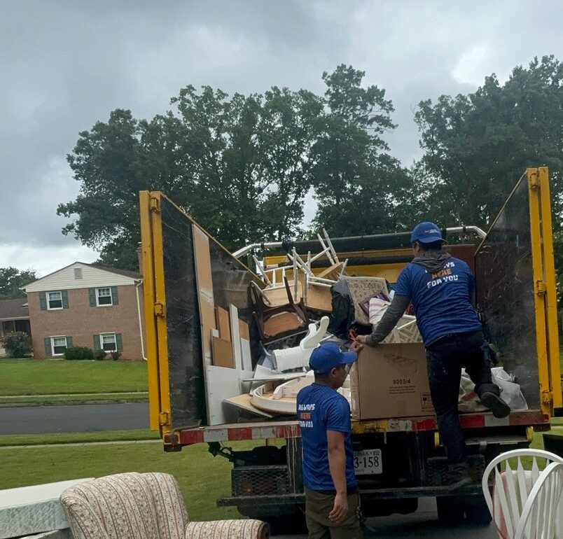 Out Junk Out crew loading chairs and household furniture into a yellow removal truck